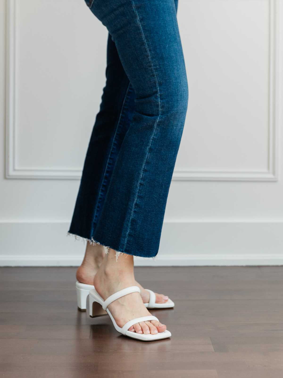 Cropped view of woman's legs wearing  minimal slide sandals with kick flares