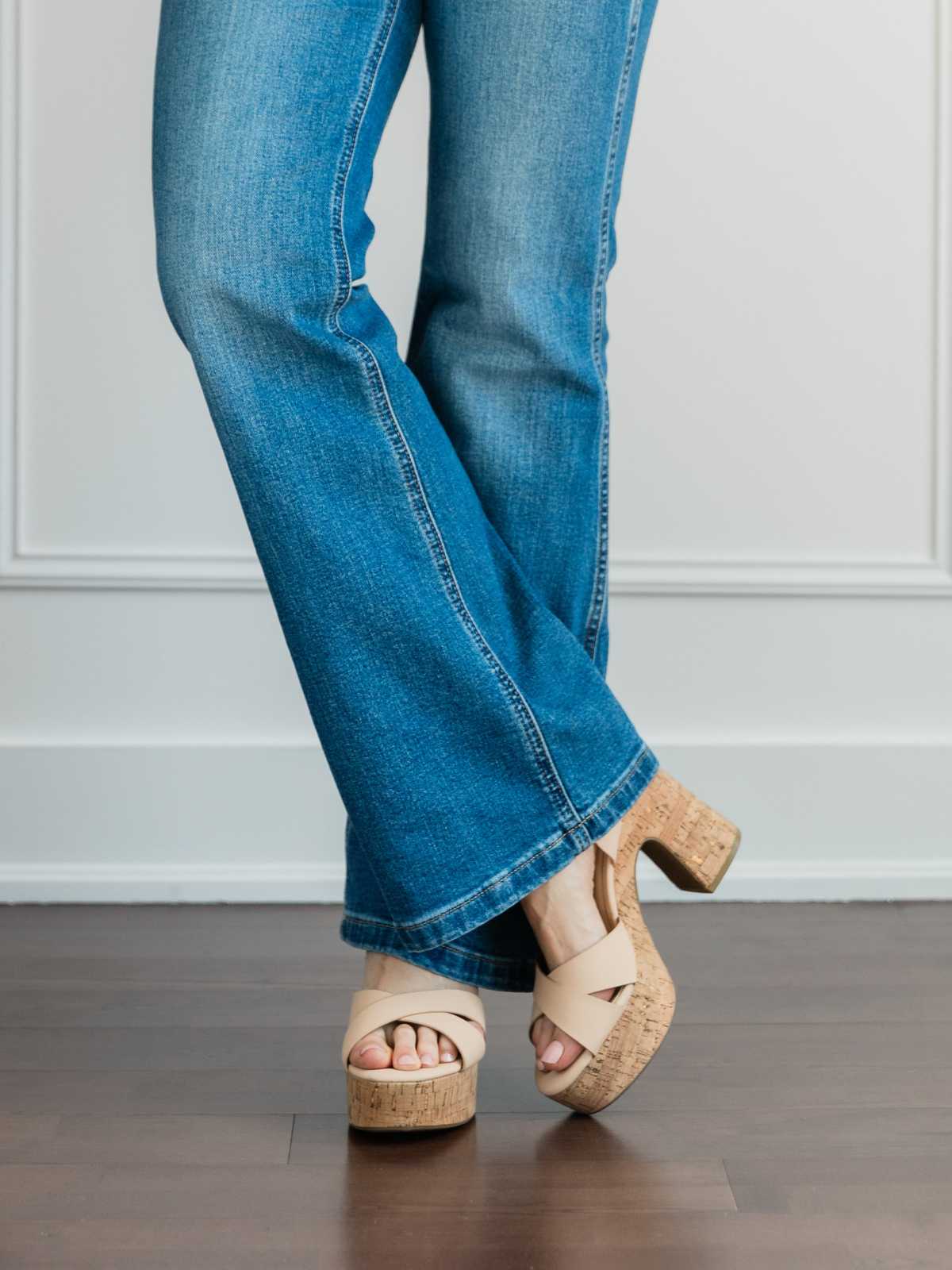 Cropped view of woman's legs wearing platform sandals with full length blue flare jeans.