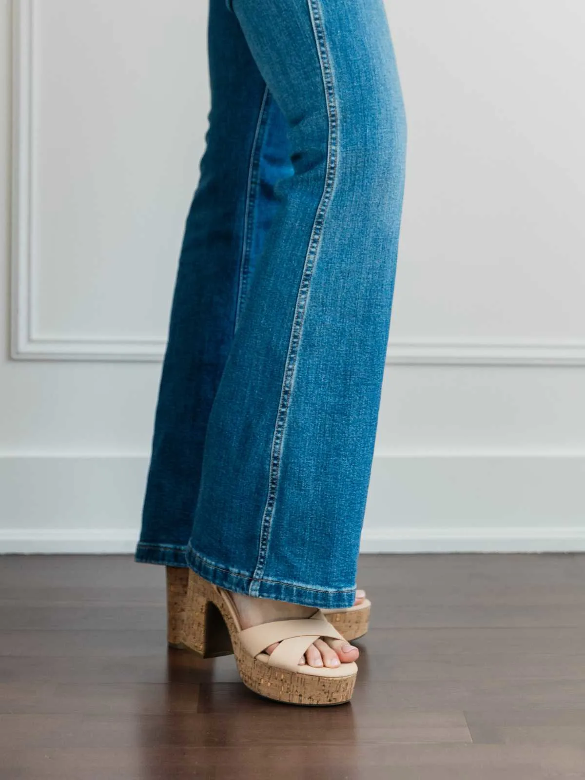 Cropped view of woman's legs wearing platform sandals with full length blue flare jeans.