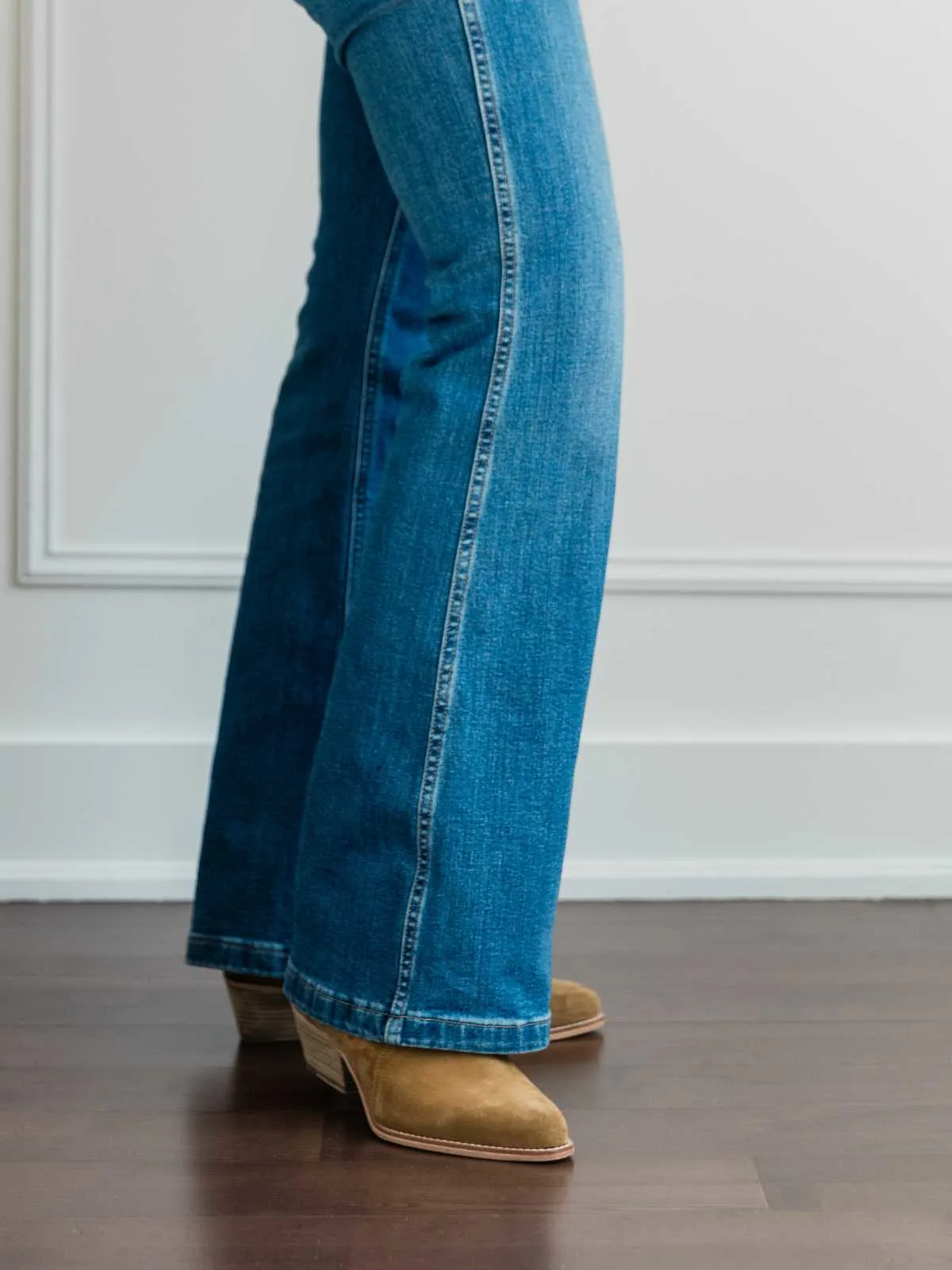 Cropped view of woman's legs wearing  western ankle boots with full length blue flare jeans.