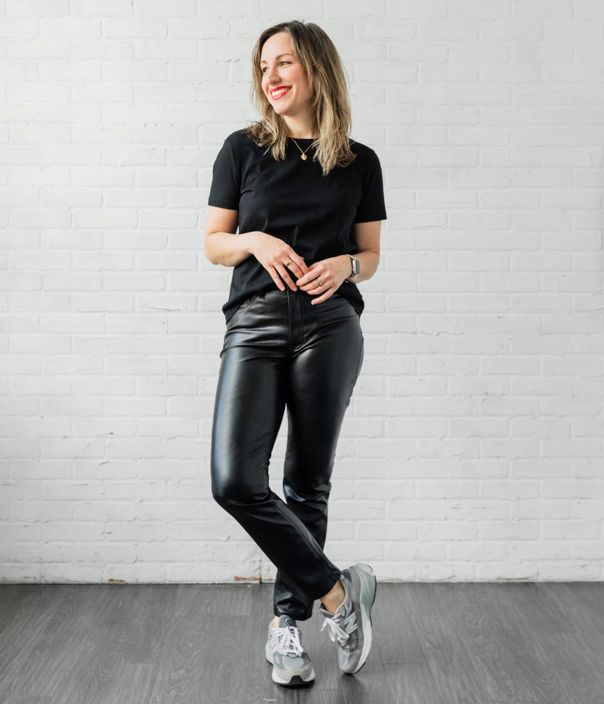 Woman posing in black leather pants black tshirt and grey sneakers